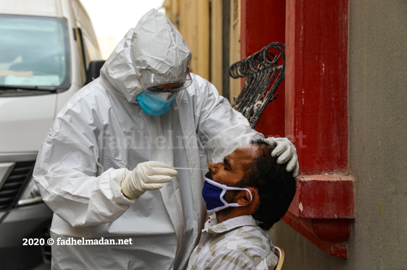 ممرض بحريني يأخذ عينة فحص فيروس كورونا المستجد قرب مجمع سكني لعمالة وافدة